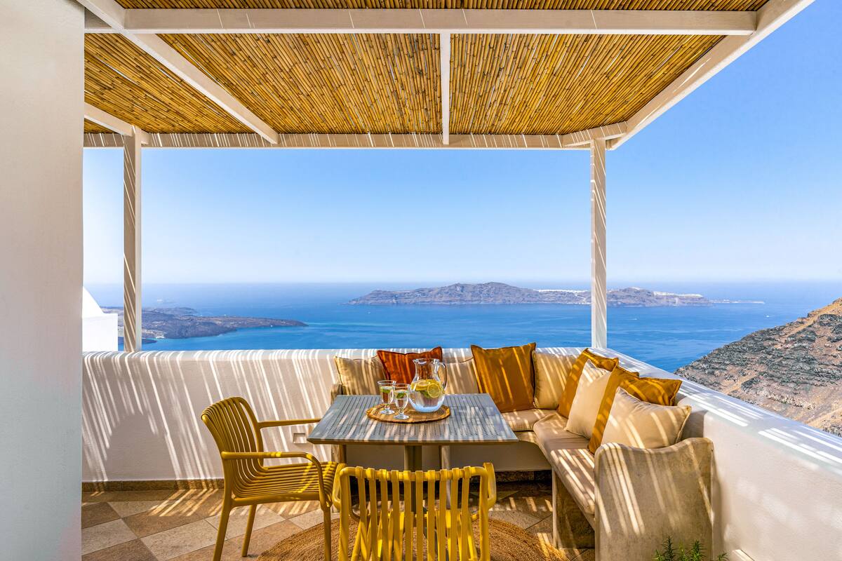 A terrace with a table set for two, overlooking a scenic coastline.
