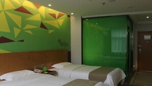 A hotel room with two beds, a wooden headboard, a green wall with geometric patterns, and a green sliding door. - Vatica Hefei Anqing West Road Nongda East Gate Hotel (Hefei)