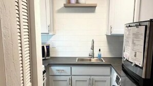 Eine kompakte Küche mit integrierter Waschmaschine, einem Edelstahl-Kühlschrank und einer kleinen Arbeitsfläche.