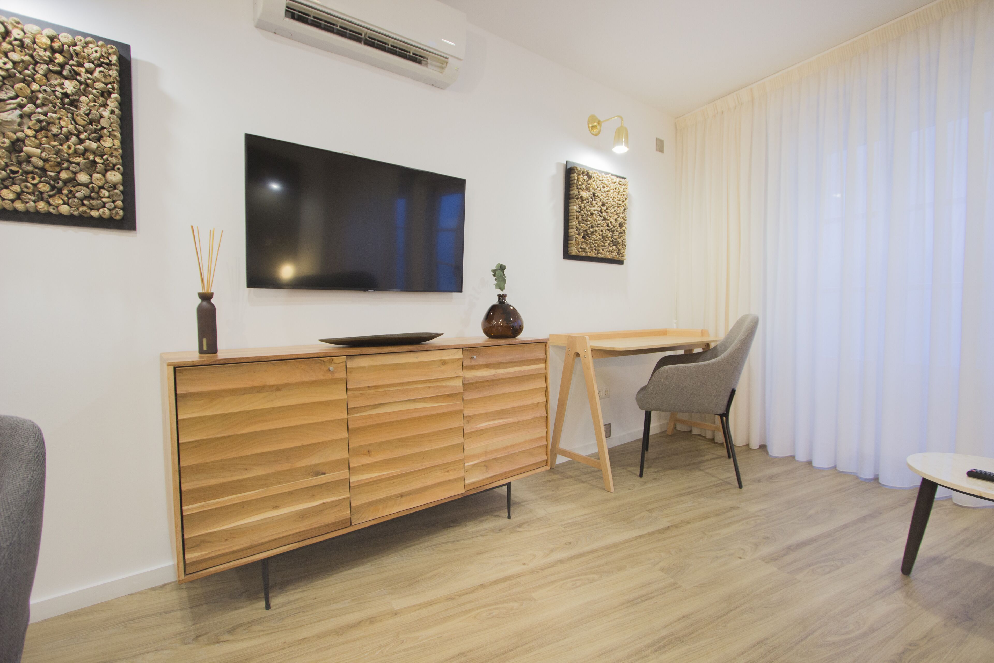 Un salon moderne avec un meuble en bois, un téléviseur à écran plat, un bureau et une chaise.