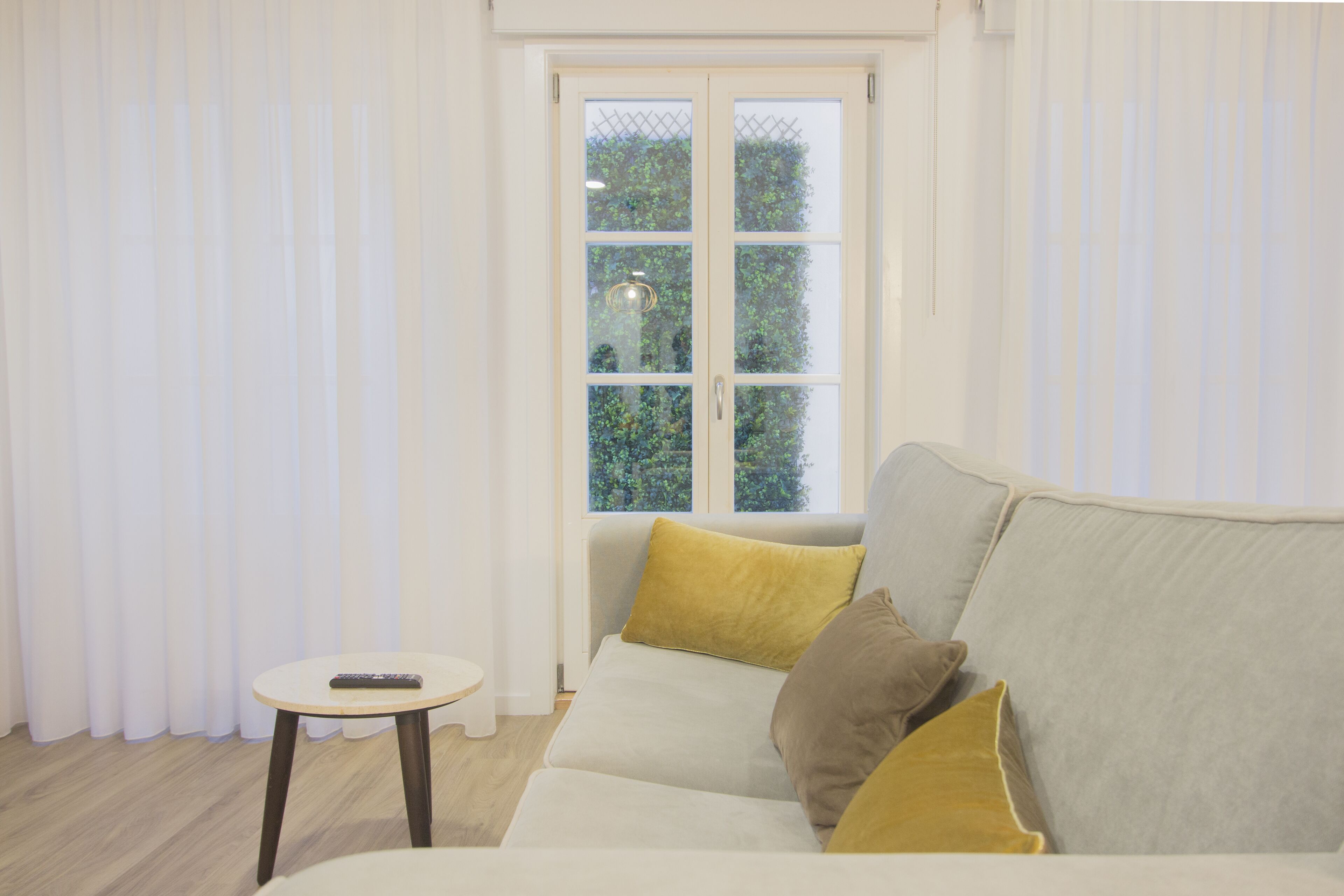 A modern living room with a sofa, a small round table, and a window with curtains.