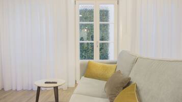 A modern living room with a sofa, a small round table, and a window with curtains.