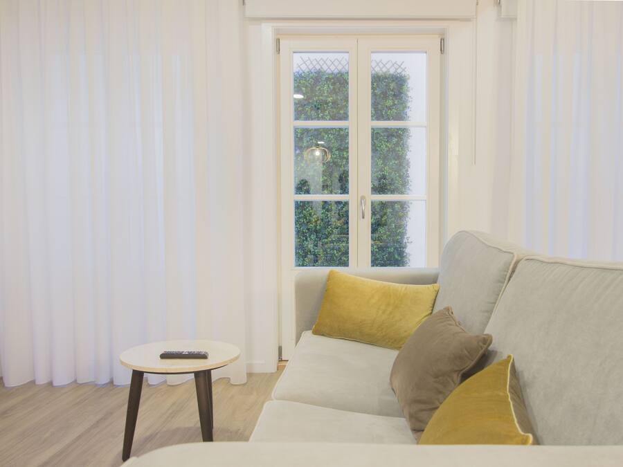 A modern living room with a sofa, a small round table, and a window with curtains.