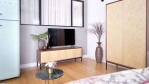 Una sala de estar moderna con televisor de pantalla plana, un mueble de madera y un amplio armario.