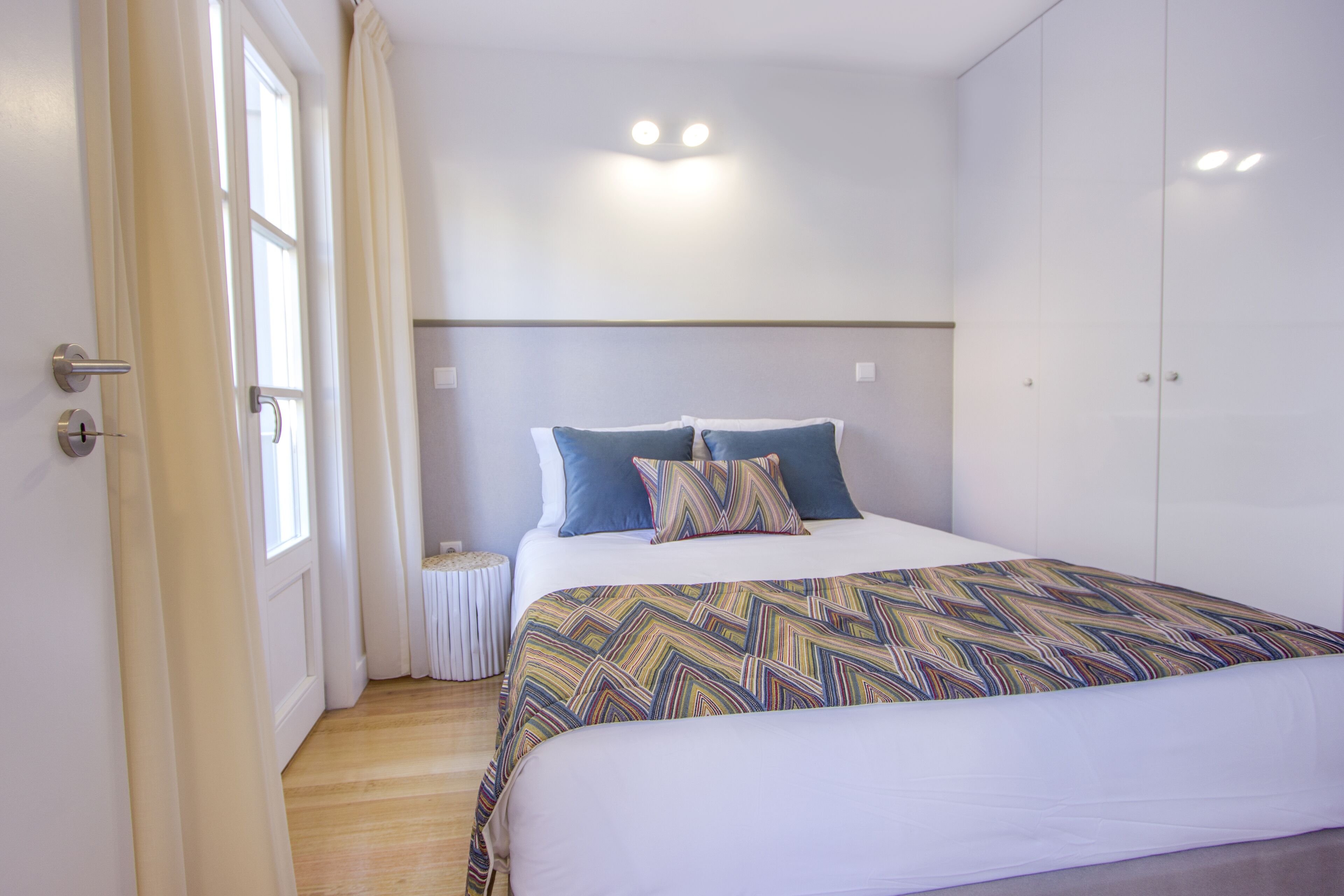 Une chambre à coucher avec un lit, des rideaux, une table de chevet et une armoire.