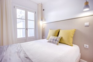 Un dormitorio con una cama, dos almohadas, una ventana y una lámpara.