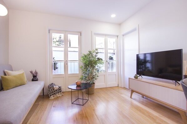 A modern living room with a sofa, a flat-screen TV, a potted plant, and a small table. - Santa Luzia Apartments By Guestify (Guimarães)