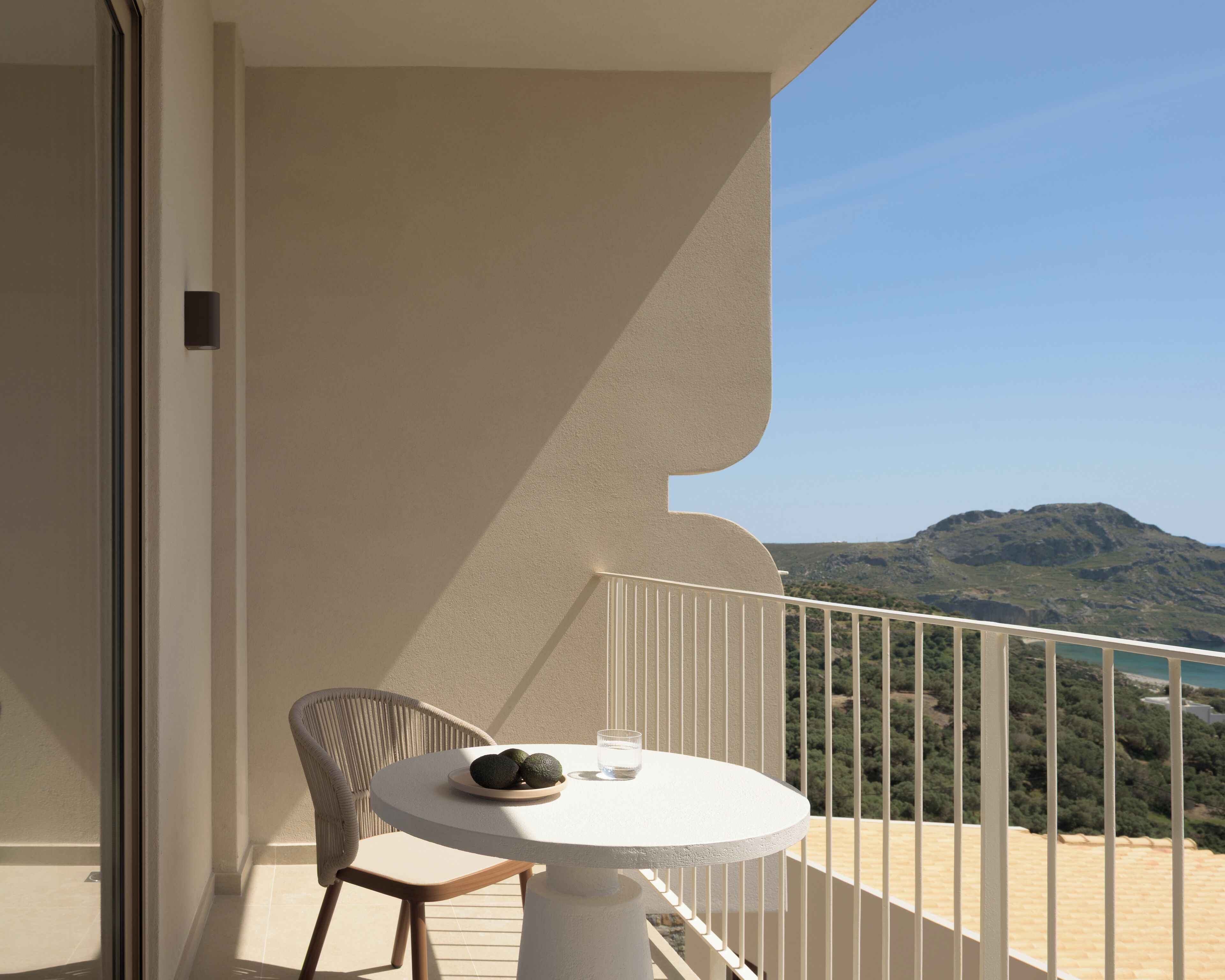 A balcony with a round table, a chair, and a plate of avocados.