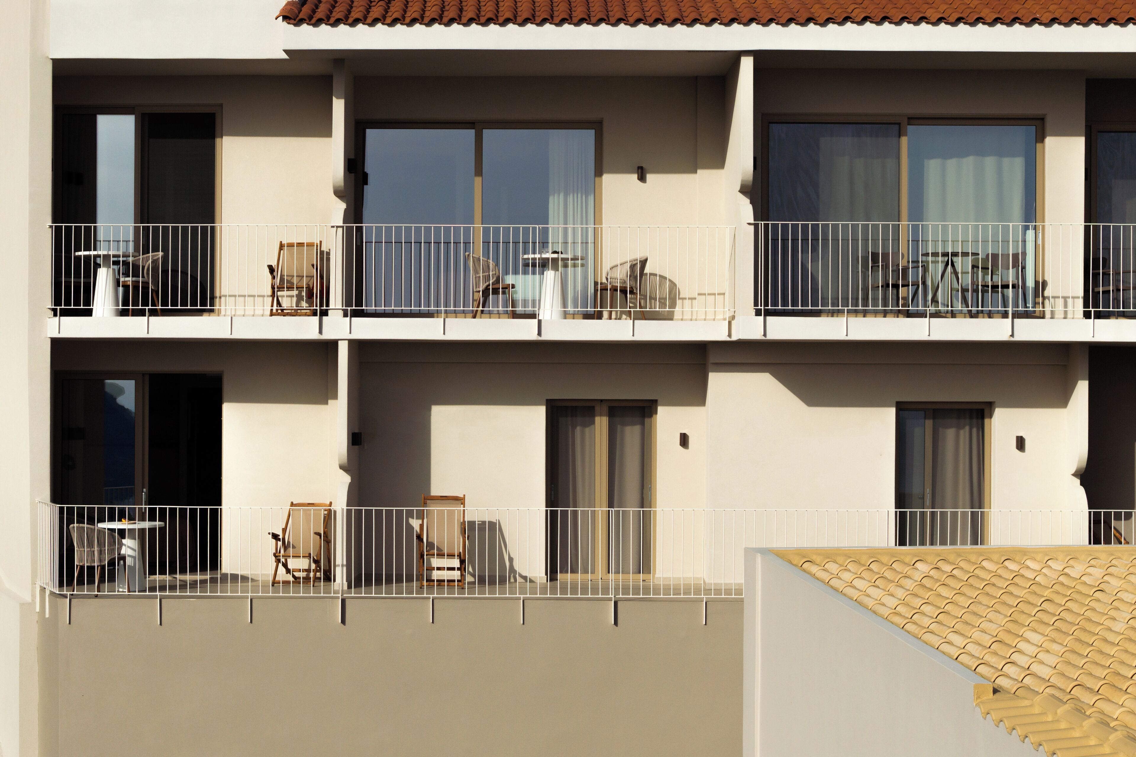 A multi-story building with balconies, each equipped with outdoor furniture and railings.
