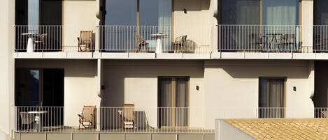 A multi-story building with balconies, each equipped with outdoor furniture and railings.