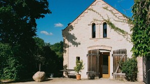 A rustic stone building with a sloped roof, a wooden door, and a bench outside. - REMISE LOFT: Spacious apartment with balcony, loggia window and water access (Werder (Havel))