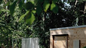 Een houten hut met een deur en een metalen constructie met een witte gordijn.