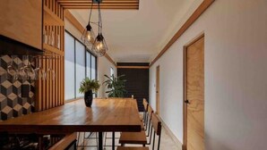 A dining area with a long wooden table, benches, and hanging pendant lights. - Pinoli House, Xochimilco Neighborhood (Oaxaca)