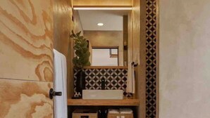 A narrow hallway with wooden walls, a white door, and a small kitchenette area with a sink and storage baskets. - Pinoli House, Xochimilco Neighborhood (Oaxaca)