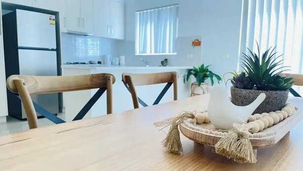 Eine moderne Küche mit weißen Schränken, einem Holztisch und einem dekorativen Mittelstück.