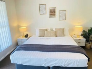 Relax in a stylish room with a large bed, bedside tables, and a potted plant.