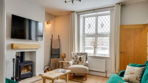 Un salon chaleureux avec une cheminée, un téléviseur, un fauteuil confortable et un canapé vert.