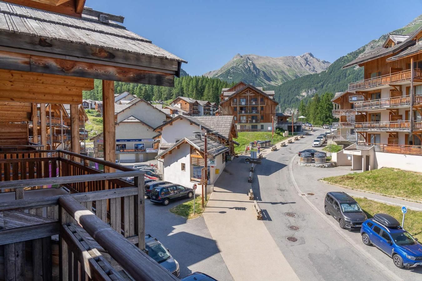 Une station de montagne avec des bâtiments en bois, une route principale et des voitures garées.