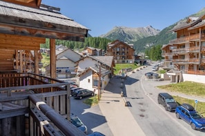 A mountain resort with wooden buildings, a main road, and parked cars.