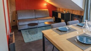 A modern living room with a sofa, coffee table, and dining table set for two.