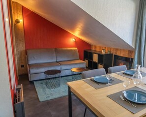 Ein modernes Wohnzimmer mit einer Couch, einem Couchtisch und einem Esstisch für zwei Personen.