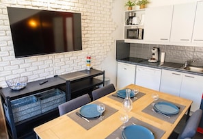 A modern kitchen with a flat-screen TV, white cabinets, and a dining area set with blue plates and glasses.