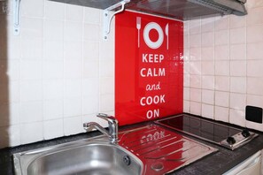 A kitchen with a red sign that says 'KEEP CALM and COOK ON' and a stainless steel sink.