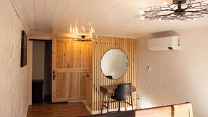 A wooden interior with a round mirror, a desk, and a chair.