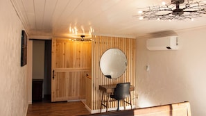 A wooden interior with a round mirror, a desk, and a chair.