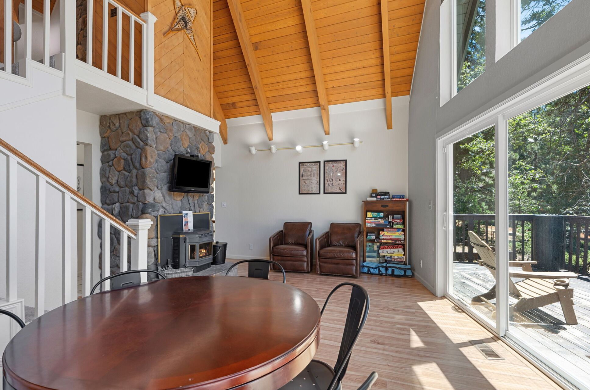 A spacious living area with a stone fireplace, comfortable seating, and a large window offering a view of the outdoors.