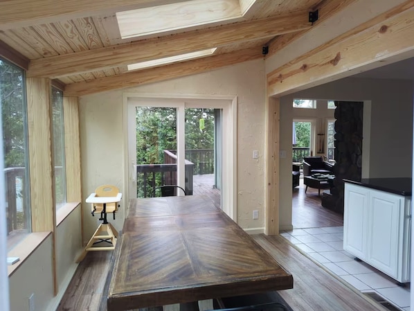 A spacious kitchen with a large wooden table, a stone accent wall, and a view of the outdoors.