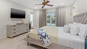 Ein Schlafzimmer mit Bett, Fernseher, Deckenventilator und Blick ins Freie.