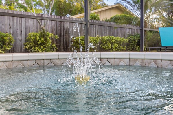 A swimming pool with water splashing from a fountain.