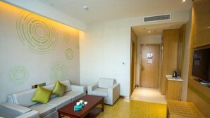 A modern living room with a sofa set, a coffee table, and a TV. - Greentree Inn Hefei Lujiang County No.1 Jin Street Express Hotel (Hefei)