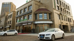 A building with multiple floors, featuring a prominent sign with Chinese characters. There are two cars parked in front, and the building has a modern architectural style with large windows. - Greentree Inn Hefei Lujiang County No.1 Jin Street Express Hotel (Hefei)