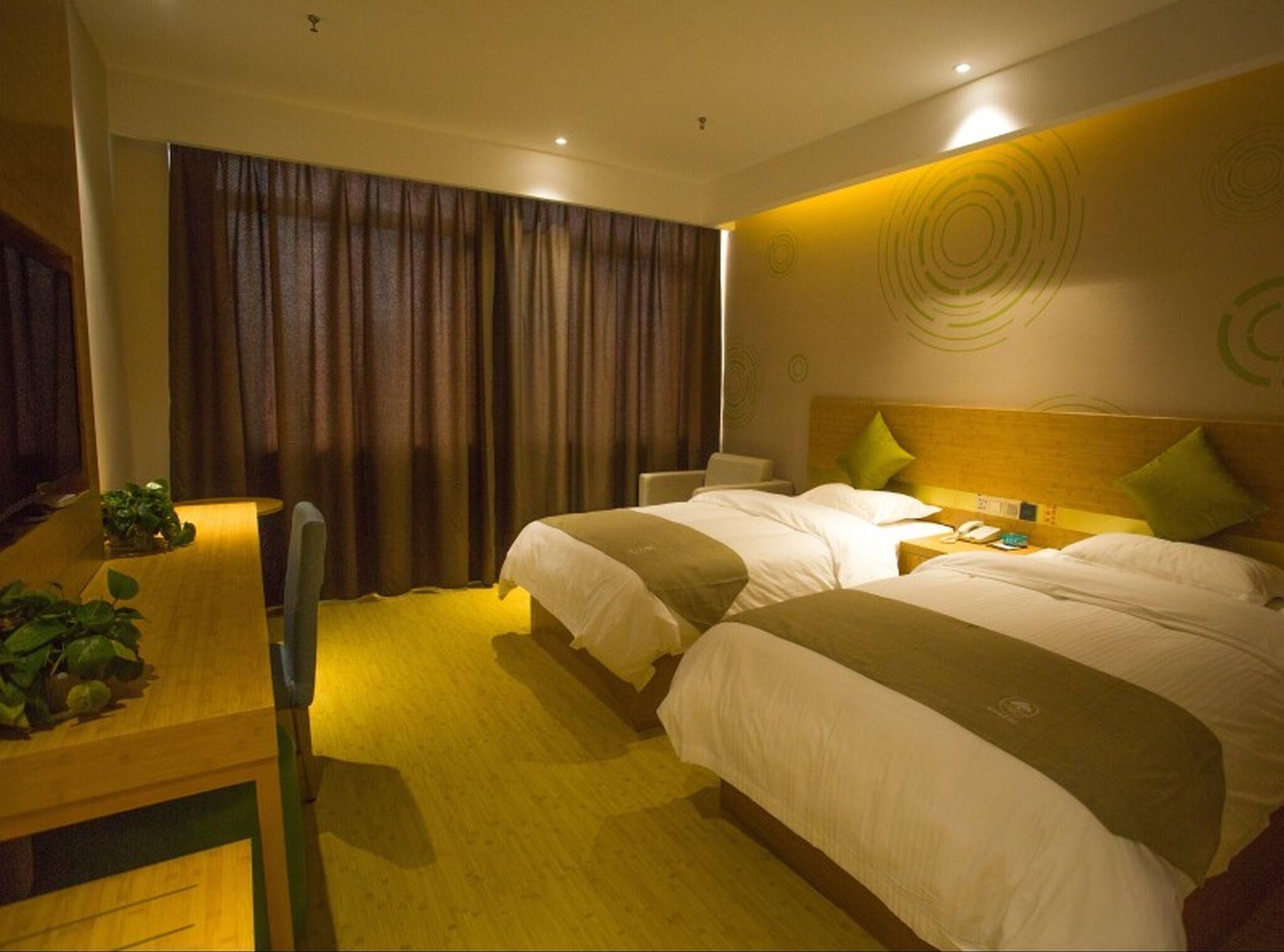 A hotel room with two beds, a desk, and a chair.