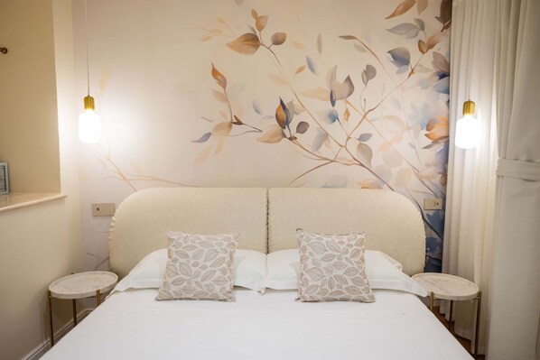 Ein Doppelbett mit zwei Kissen, ein Nachttisch, eine Wandleuchte und ein floraler Wanddekor.