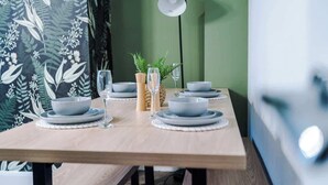 Ein Esstisch gedeckt mit Tellern, Schüsseln, Gläsern und einer Lampe.
