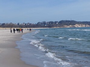 Ein Strand mit Menschen, die am Ufer entlanggehen.