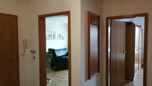 A hallway with wooden doors leading to a living area with a sofa and a wall-mounted rack. - Close to the beach and with sea views, apartment in a quiet, central location (Göhren)