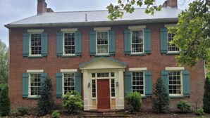 A two-story brick building with a central entrance, flanked by windows with shutters, and a small porch area. - Harriet's Highlands Hideaway (Mount Pleasant)