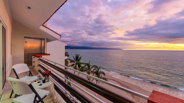 Un balcón con vista al océano al atardecer.