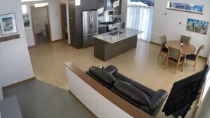 Una cocina moderna con una isla central, un comedor con mesa y sillas, y una sala de estar con sofá.