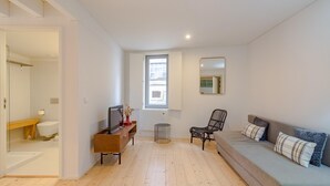 A modern living room with a sofa, a chair, a TV, and a small side table. - Porto Vitoria 5 in Oporto (Porto)