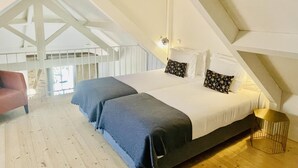 A bedroom with a large bed, a chair, and a wooden floor. - Porto Vitoria 5 in Oporto (Porto)