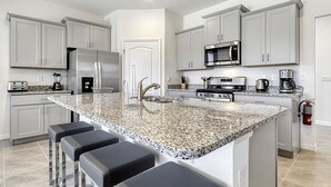 A modern kitchen with granite countertops, stainless steel appliances, and grey cabinetry. - ⛱ Solterra Resort - 5★ Clubhouse - Champions Gate Area - Extended Pool & Deck ✈ (Davenport)