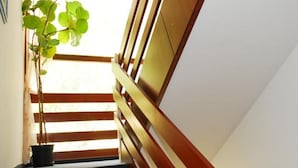 A staircase with wooden railings and a potted plant at the bottom. - Hotel Orion Varkert (Budapest)