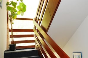 A staircase with wooden railings and a potted plant at the bottom. - Hotel Orion Varkert (Budapest)
