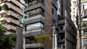 A multi-story building with balconies, a parked car, and a motorcycle on the street.