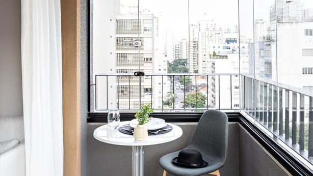 A balcony with a round table, a chair, and a potted plant.